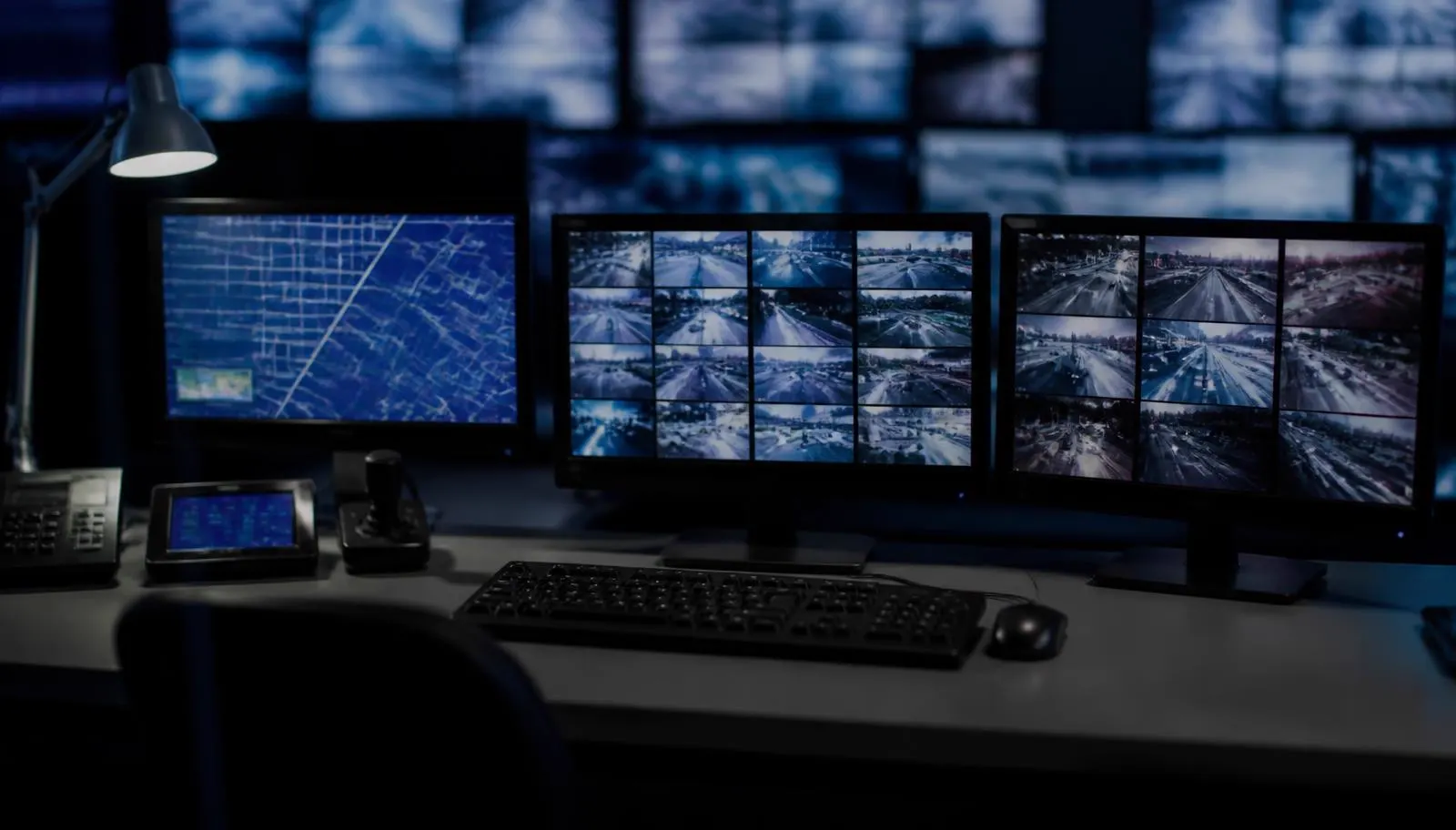 Meldkamerwerkplek met beeldschermen vol camerabeelden